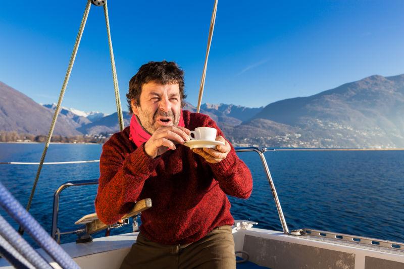 帆船上休息喝咖啡的男子