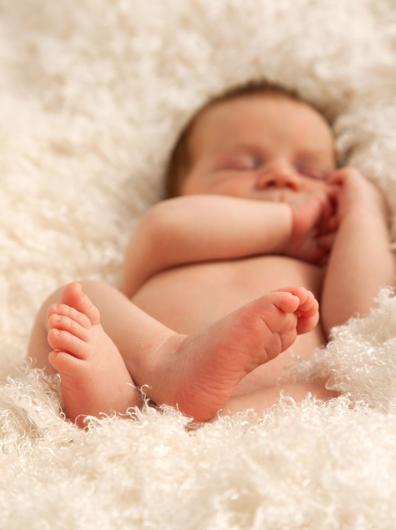 可爱的一周大婴儿躺在白毯子上