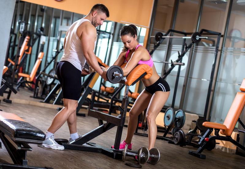 在健身房锻炼杠铃的健身夫妇