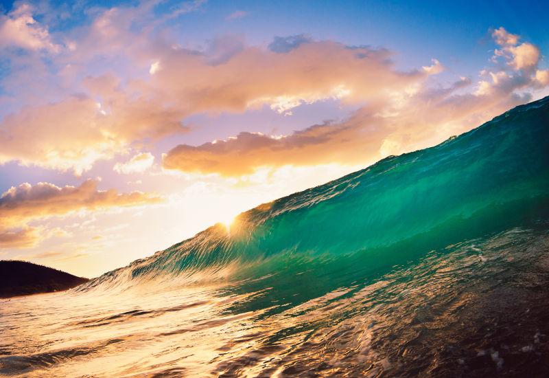 日落时分有晚霞的天空背景下翻滚的蓝色海浪