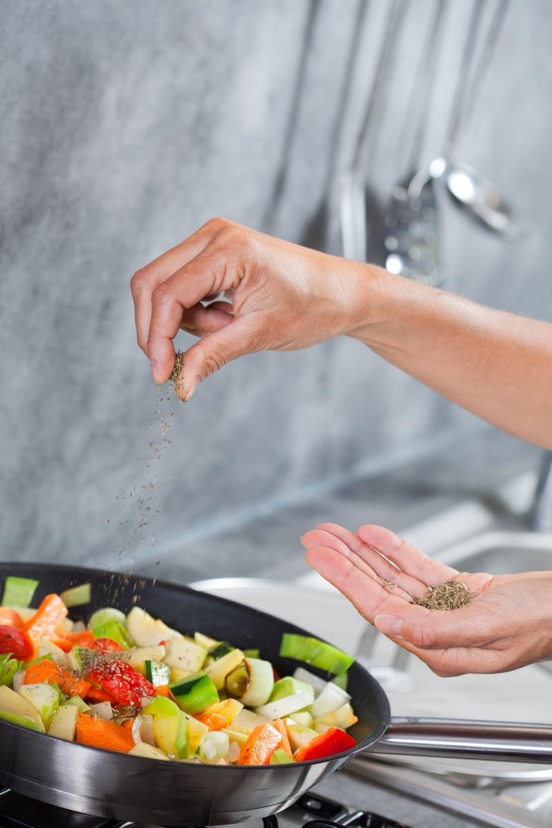 厨房里厨师正在往锅里放盐