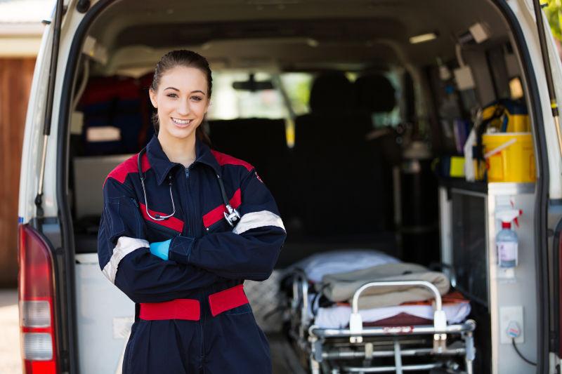 快乐的女医务人员站在救护车前