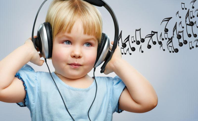 灰色背景下戴着耳机听音乐的小女孩