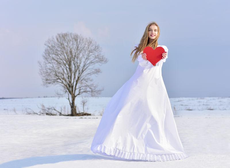 雪地里手里捧着一颗红心的美女