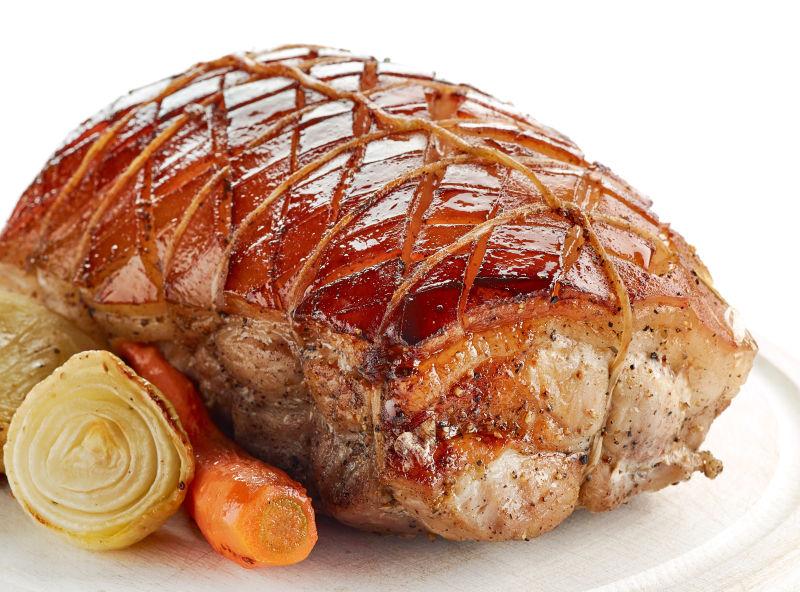 白色盘子上面的烤猪肉和蔬菜