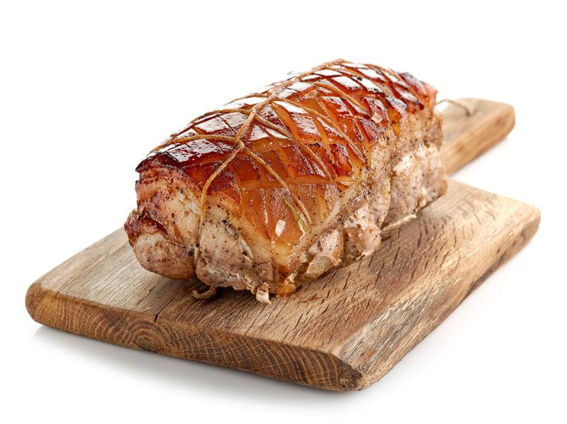 白色背景砧板上的一块烤猪肉