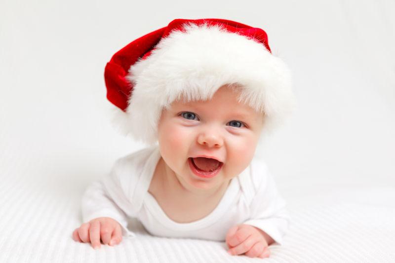 床上戴着圣诞帽大笑的婴儿