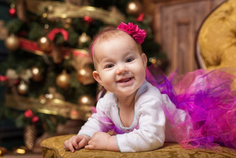 可爱快乐的小女孩躺在圣诞树下的沙发上