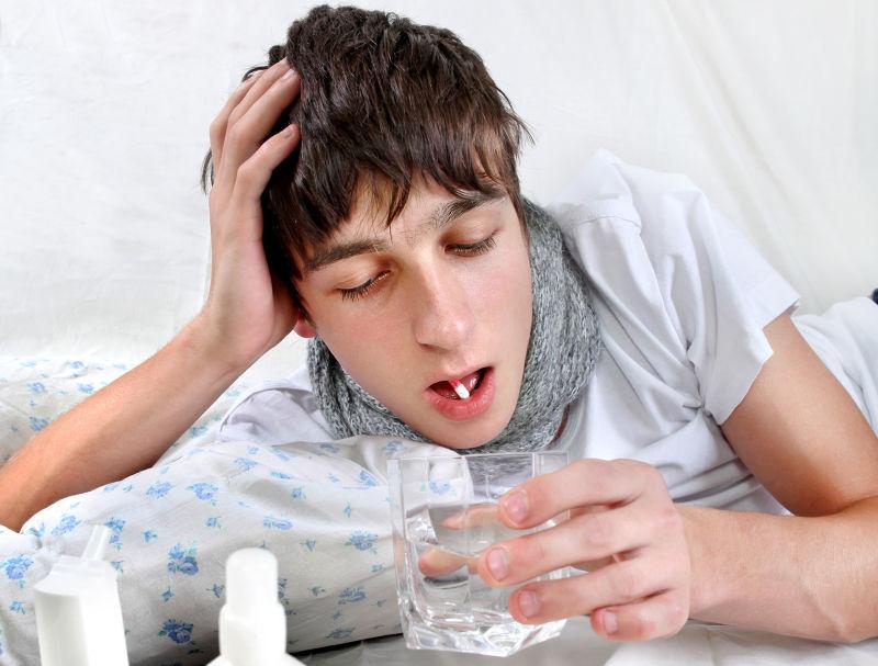 正在床上吃药的生病的年轻人