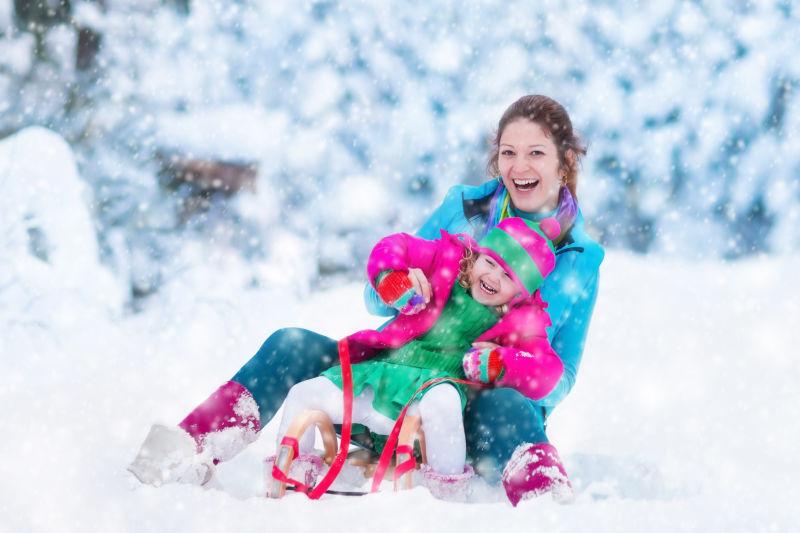在雪地里玩雪橇的母女俩