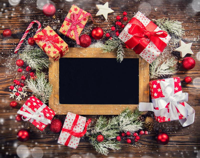 空白黑板边的各种圣诞装饰品和圣诞礼物