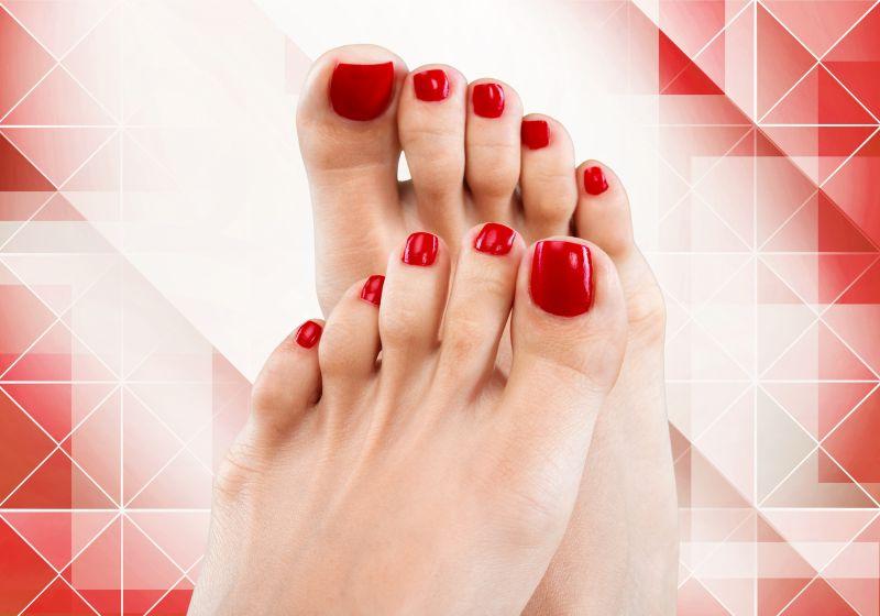 红色和白色几何图案背景下的红色双脚美甲