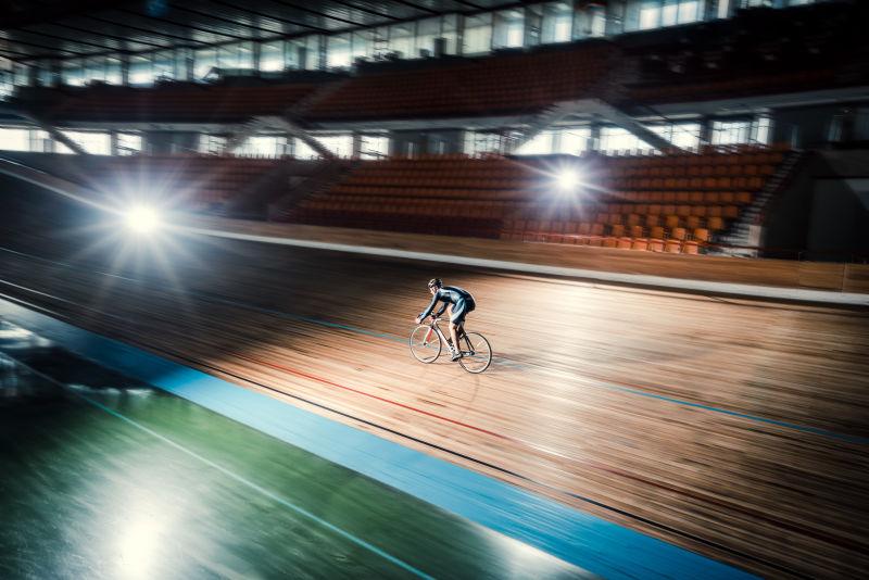 灯光下在跑道上骑自行车的运动员