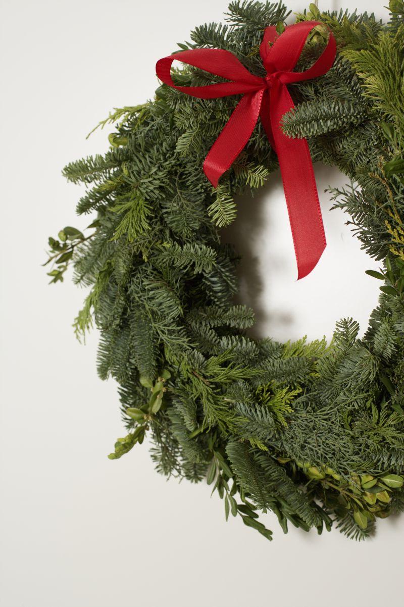 白色墙上的圣诞花环系着红色的彩带