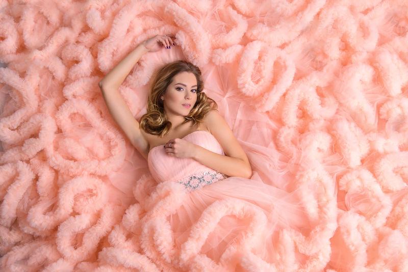 躺在粉色婚纱上的美女模特