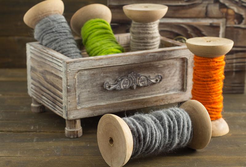 木桌上木盒子里的彩色羊毛纱线线轴