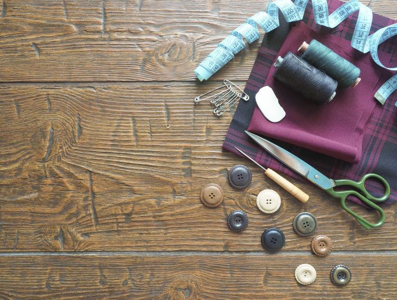 老旧木桌上的针线纽扣和剪刀等缝纫工具