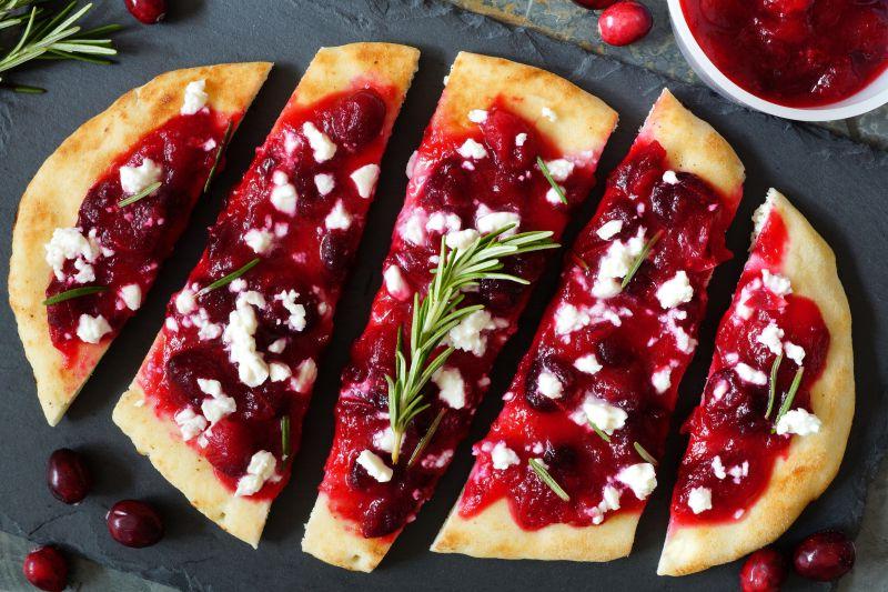 黑色托盘上切开的加了蔓越莓酱和山羊奶酪的馅饼