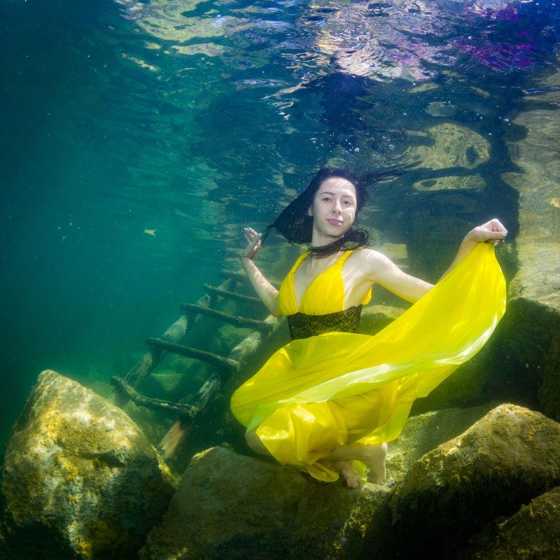 穿着一件裙子在水下楼梯的年轻优雅的女人