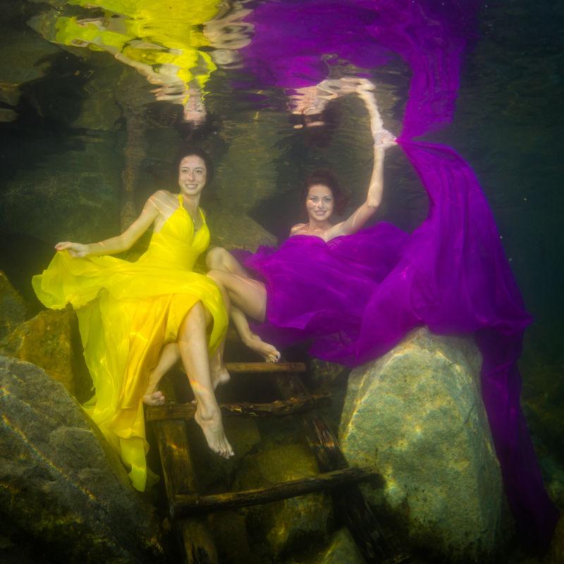 穿着裙子的两名优雅的女人在水下楼梯上