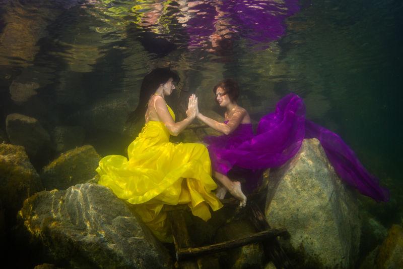 穿着同样服饰的两个优雅的女人在水下楼梯上