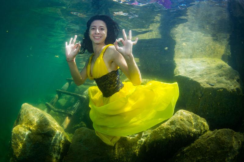 在水下楼梯旁微笑的年轻优雅的女人穿着一件裙子