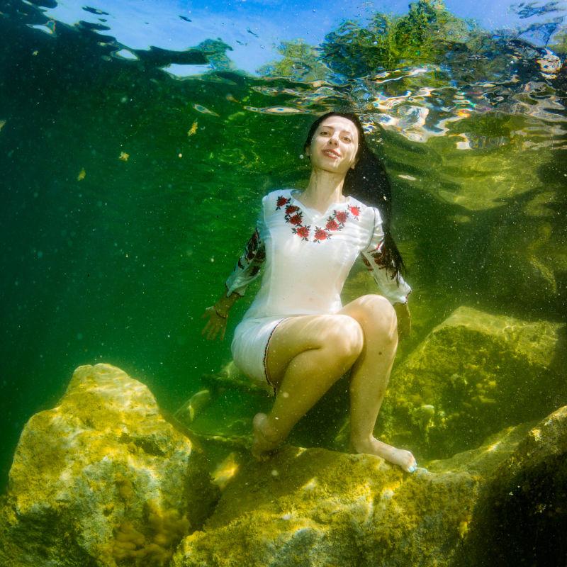 坐在水下楼梯上穿着乌克兰刺绣的年轻优雅的女子