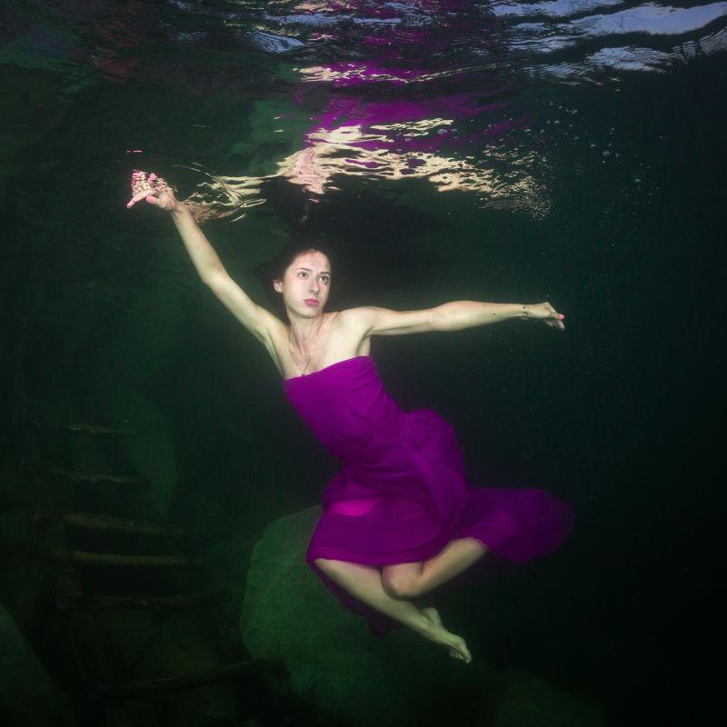 在水下的年轻的优雅女人穿着一件裙子