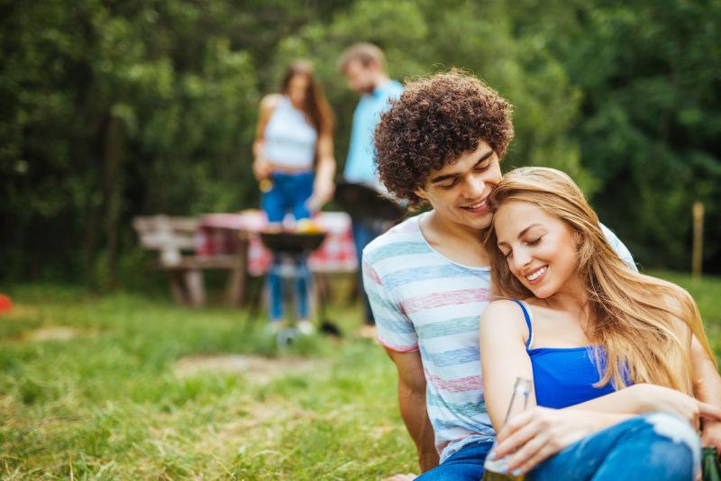 两个年轻的情侣在草地上拥抱