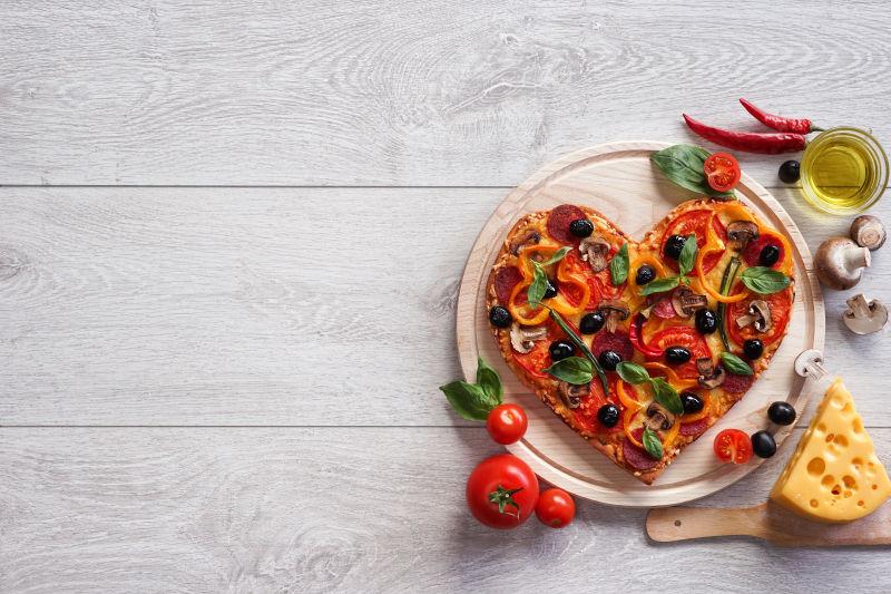 白色木制背景中的心形披萨饼