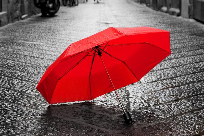 下雨旧镇鹅卵石街上的红色雨伞
