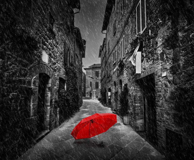 一个古老的意大利小镇的黑暗狭窄街道上的红色雨伞