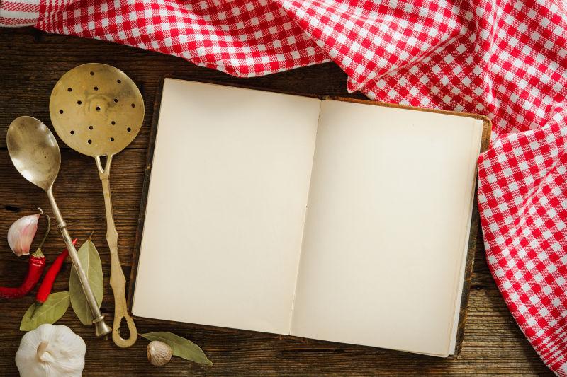 木桌上的空白的书红格餐布和餐具