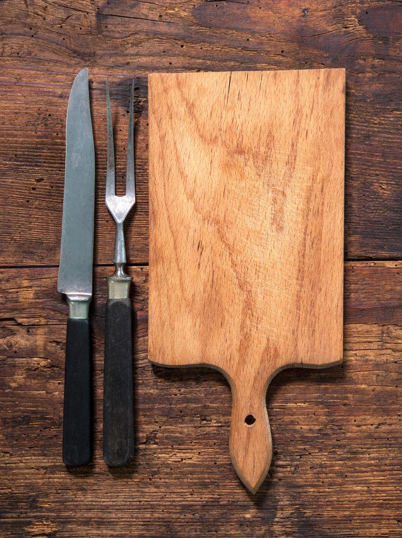 木质桌板上的菜板和刀叉