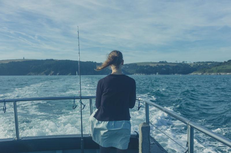 船尾的孕妇看着蔚蓝色的大海