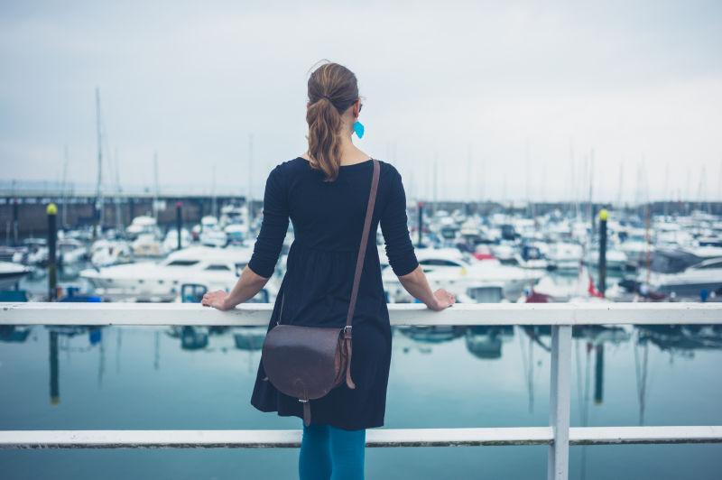 倚着护栏的孕妇看着码头