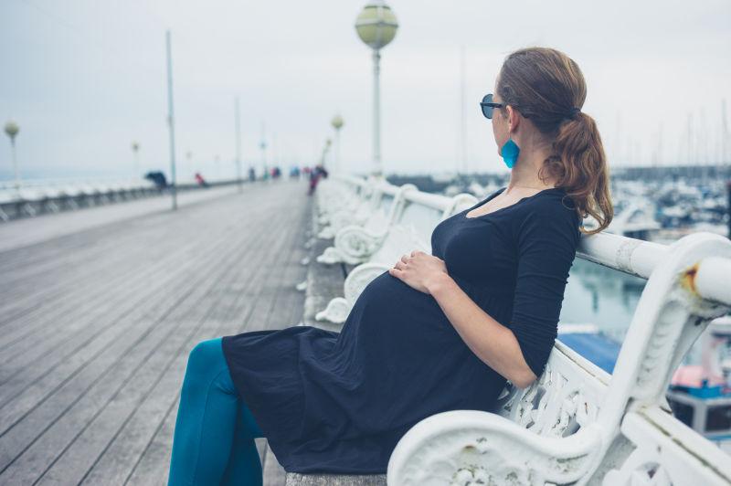 码头的休息椅上的黑衣孕妇