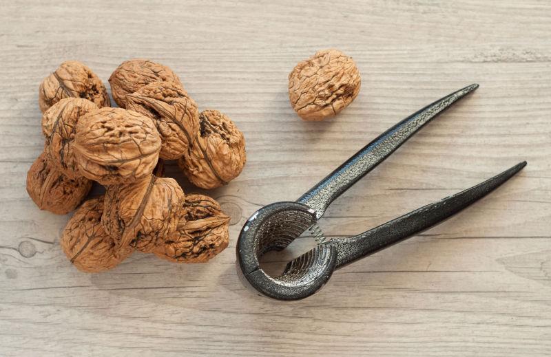 木桌上的成熟的核桃和夹核桃的工具