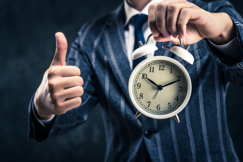 商务手拿闹钟竖起大拇指