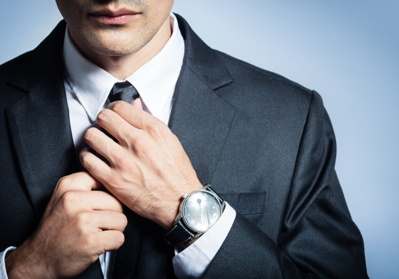 手上带着手表的男人在穿西装系领带