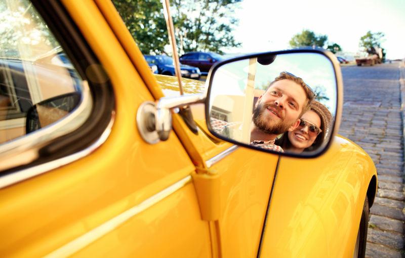 黄色敞篷车的后视镜里倒映着外国情侣