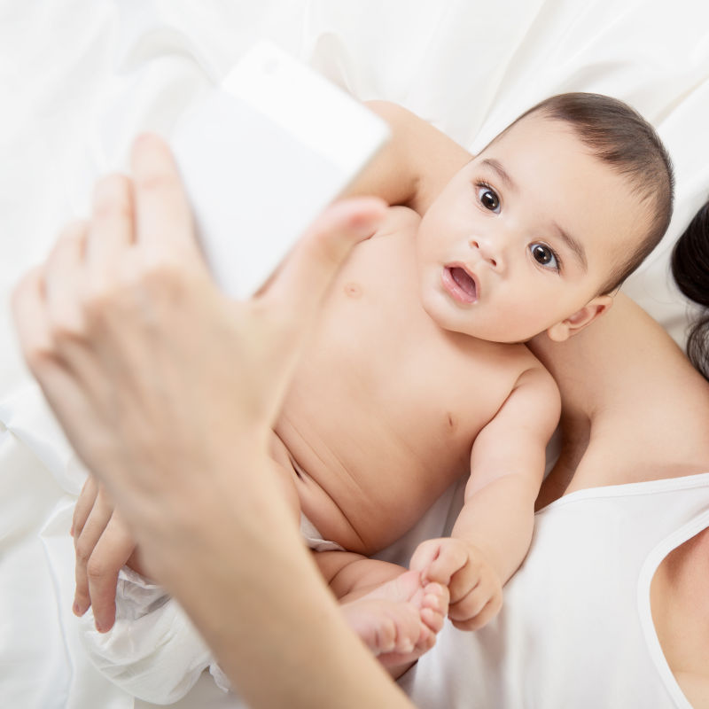 与自己宝宝玩耍拍照的妈妈