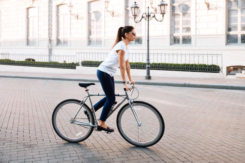 带着墨镜在城市街道骑自行车的女孩