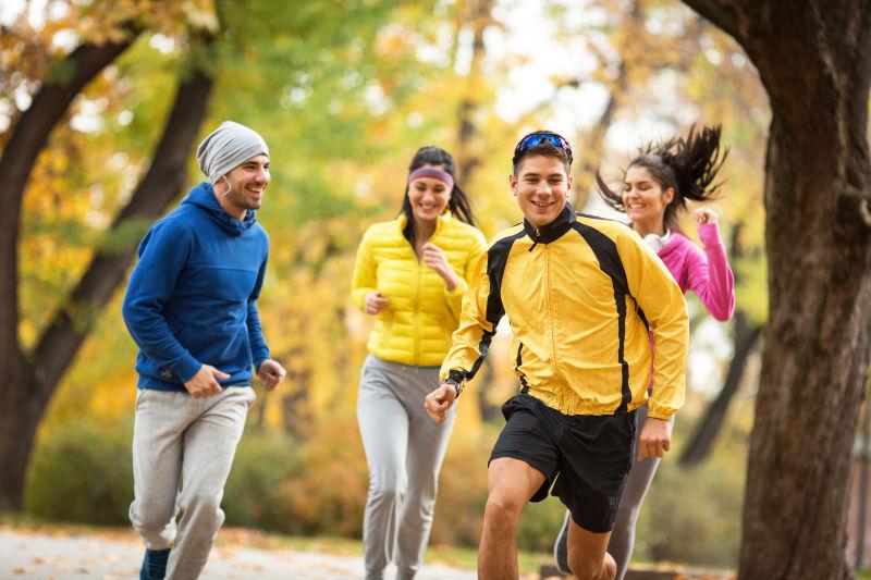 在秋天公园里玩耍打闹的四个年轻人