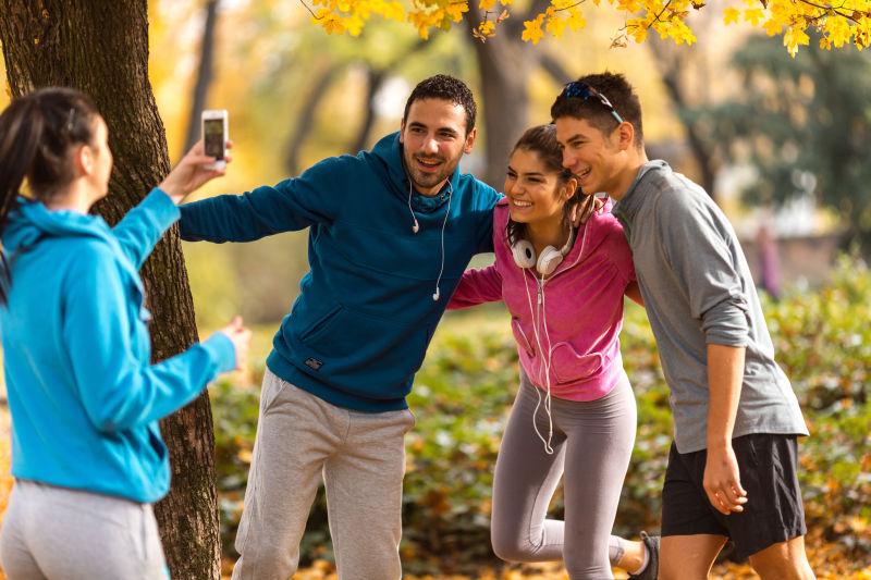 公园里蓝衣女人在给她三个朋友拍照