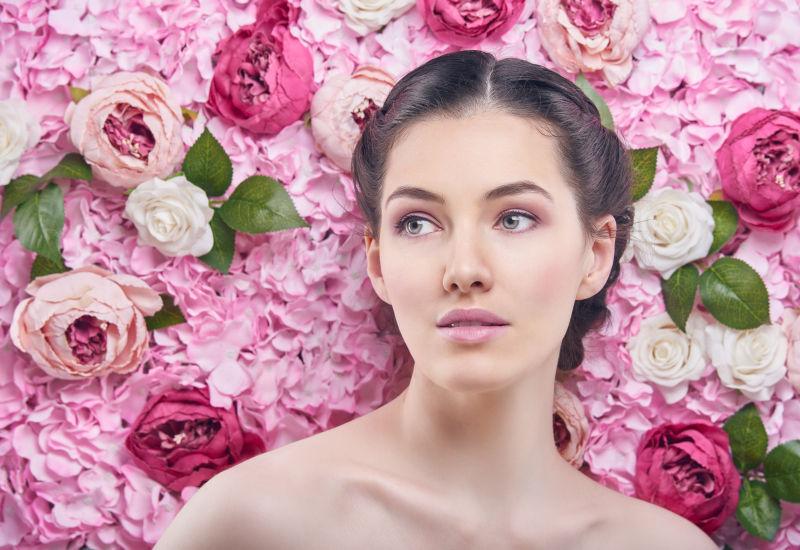 粉色花朵背景前半裸的美丽年轻女子