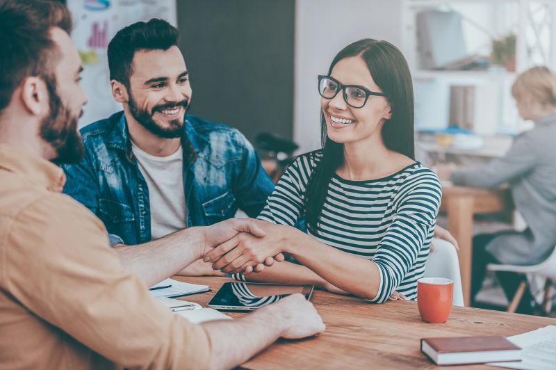在办公室里握手的年轻男女