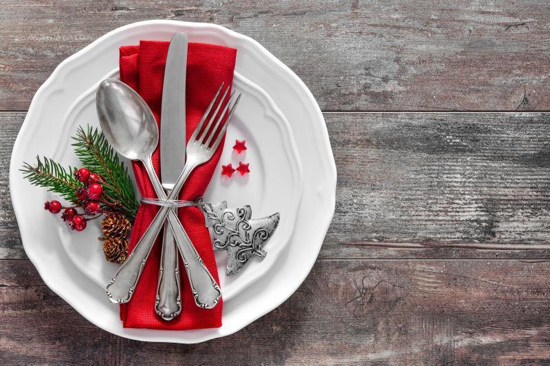 木桌上白色盘子里装饰着圣诞节装饰品的餐具