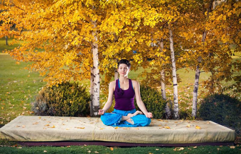 秋天公园里的美女练习瑜伽