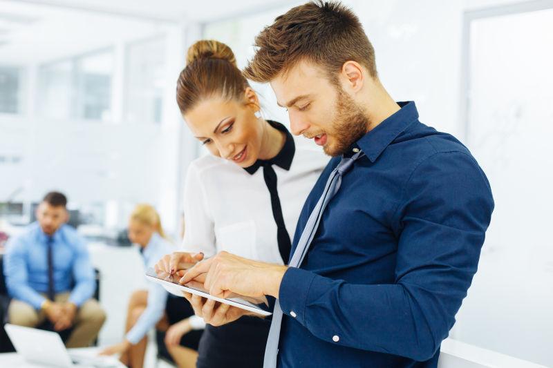 用平板电脑互相讨论的商人